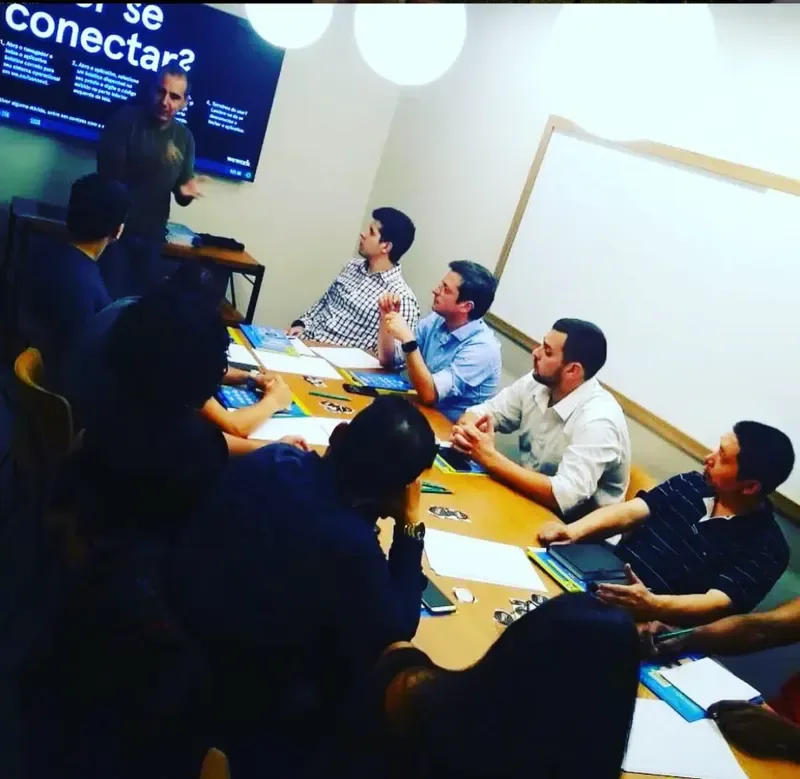 Roberto Calderon em sala de aula do ecommerce.CAMP, com a tela atrás e os alunos à mesa